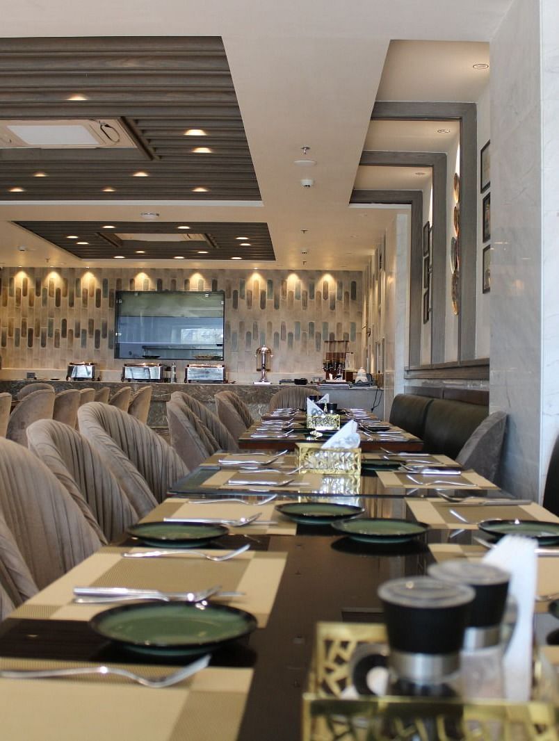 A well-arranged dining space featuring tables with chairs and neatly set cutlery at  BluSalzz Residence, Amritsar